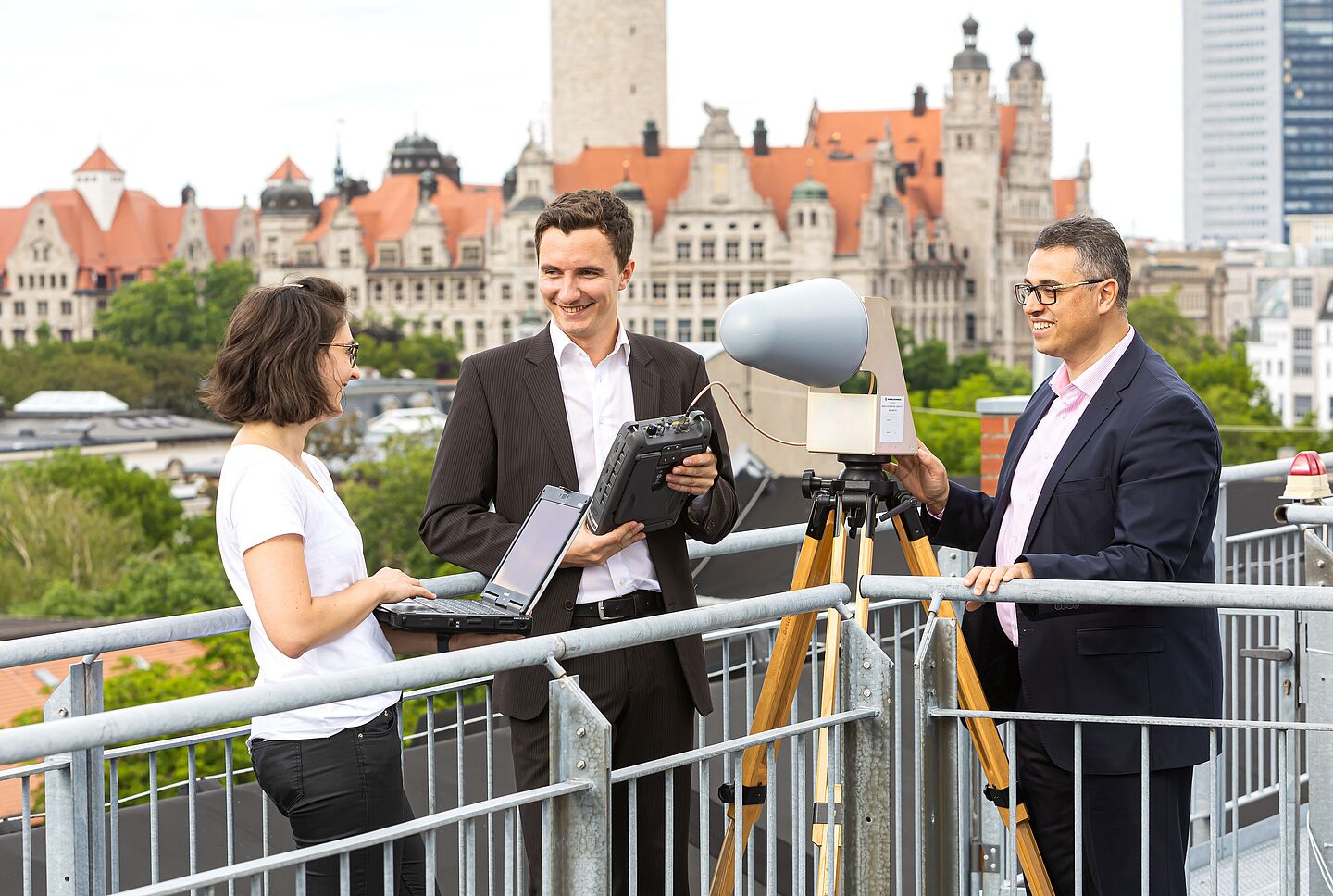 Prof. Faouzi Derbel (rechts) von der Fakultät Ingenieurwissenschaften mit Doktorandin Lydia Schott und seinem wissenschaftlichen Mitarbeiter Johannes Braun (Foto: Swen Reichhold/HTWK Leipzig) drei Personen messen etwas auf einem Dach, im Hintergrund das Neue Rathaus Leipzig
