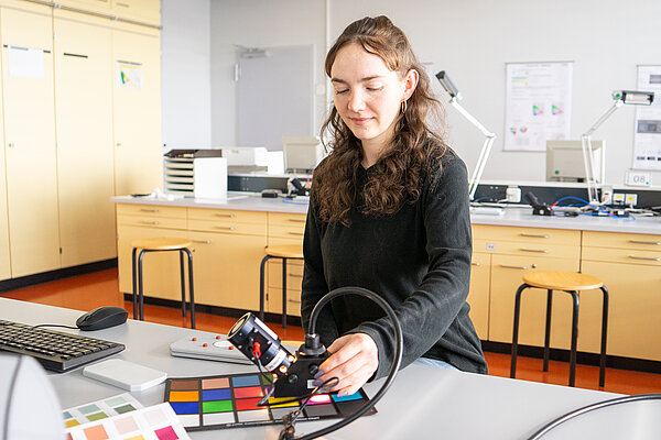 Studentin mit einer Farbkarte im Labor