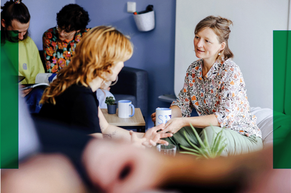 Gespräch in gemütlicher Runde Fünf Personen sitzen in einem hellen Raum, unterhalten sich und trinken Kaffee. Zwei Frauen sprechen sich direkt gegenüber.. Zur Seite Unterstützung auf Augenhöhe mit Ment4Science.