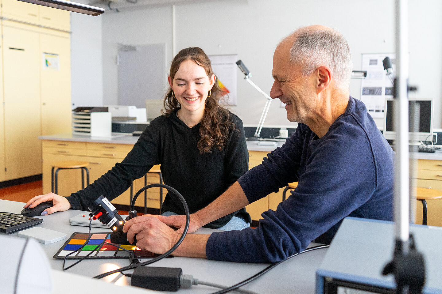 zwei Personen mit einer Farbkarte in einem Labor