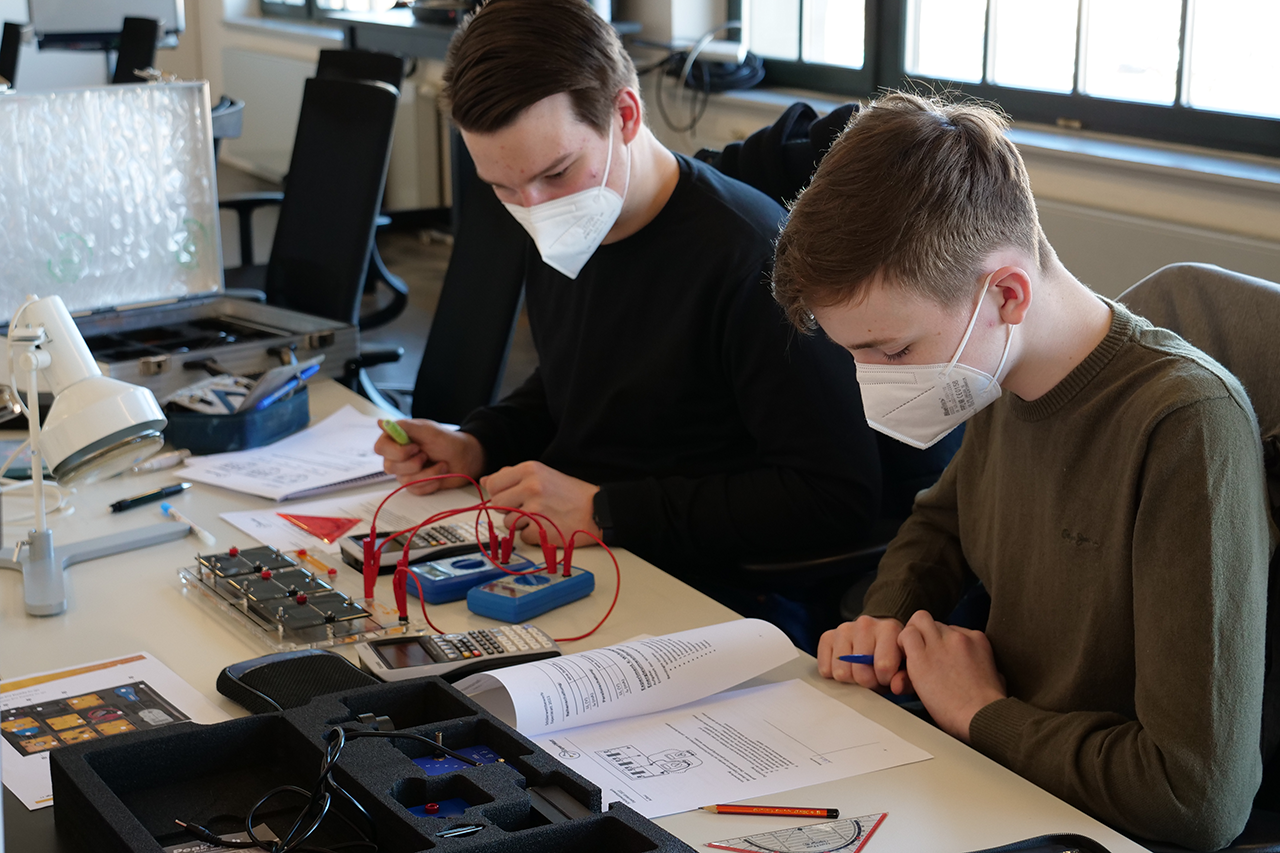 zwei Jungs mit Maske arbeiten an ihren Aufgaben