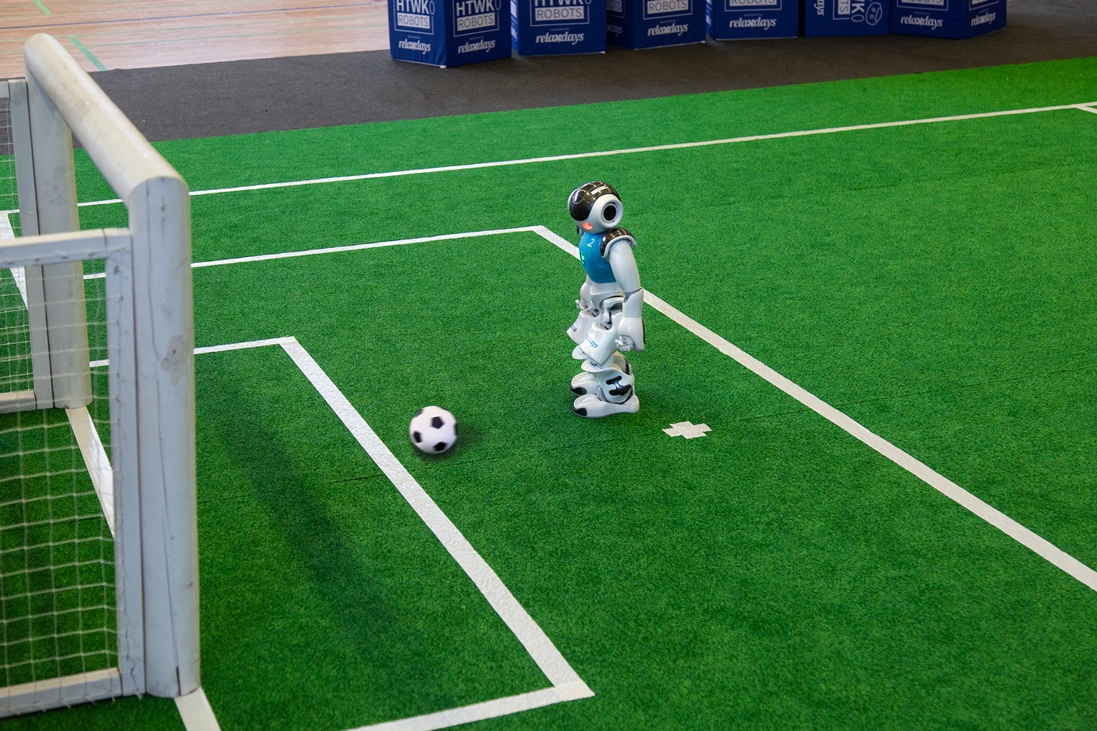 humanoider Roboter kickt Fußball ins Tor